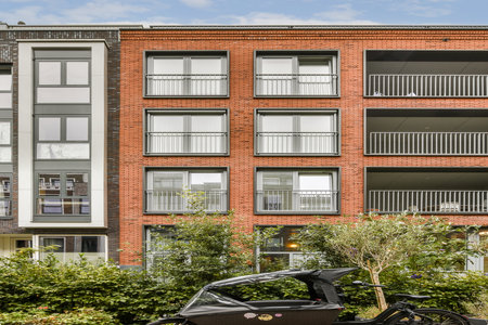 An eye-catching modern building featuring multiple balconies and greenery at the base, showcasing...