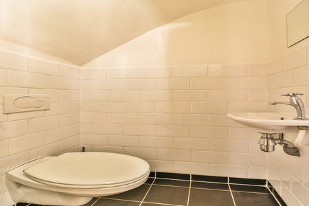 A sleek modern bathroom featuring pristine white tiles, a minimalist toilet, and an elegant wash...