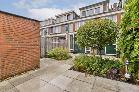 A serene backyard featuring a well-maintained garden, including a variety of plants and trees, and...