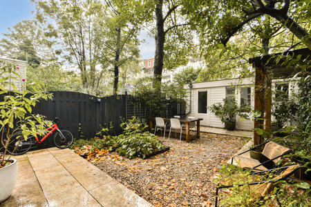 A tranquil garden space featuring a variety of greenery, seating area, and a bicycle, perfect for...