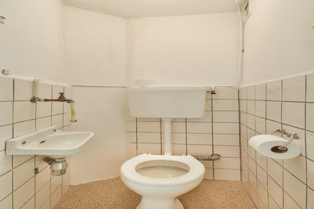 A compact and minimalistic restroom featuring a toilet, sink, and tiled walls. The design emphasizes functionality and cleanliness.の写真素材