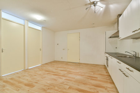 This spacious kitchen features minimalistic design with light-colored walls and wooden flooring, creating a fresh and inviting atmosphere for cooking and dining.の写真素材