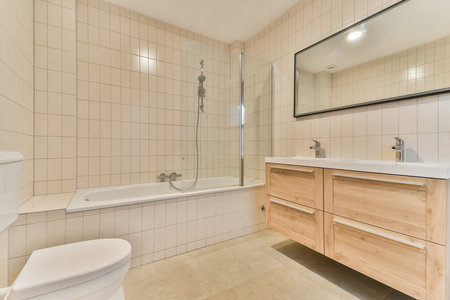 Stylish modern bathroom featuring a sleek shower, wooden cabinets, and minimalistic decor for a fresh and clean aesthetic.の写真素材