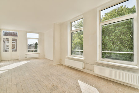 Spacious room with large windows allowing natural light, featuring minimalist decor and light-colored walls, creating an inviting atmosphere.の写真素材
