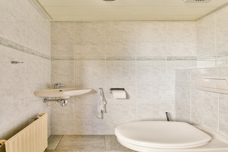 A clean and contemporary bathroom featuring tiled walls, a stylish sink, and a toilet. The design emphasizes simplicity and functionality, perfect for modern living.の写真素材