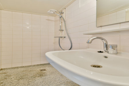 A sleek, modern bathroom showcasing a white sink and contemporary shower setup, emphasizing clean lines and minimalistic design.の写真素材