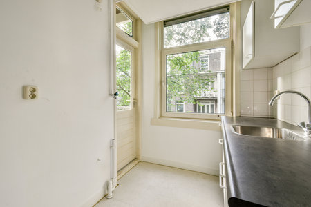 Bright and airy kitchen featuring large windows inviting natural light, showcasing a clean and minimalistic design with modern fixtures.の写真素材