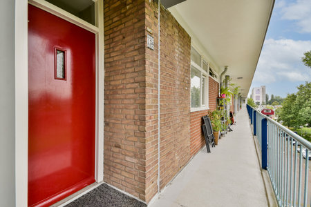 A vibrant red door stands out on a modern apartment buildings walkway, showcasing contemporary architecture and inviting atmosphere.の写真素材