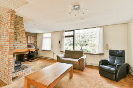 Modern living room featuring a brick fireplace, comfortable seating, and large windows that invite natural light, creating a warm and inviting atmosphere.の写真素材