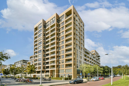 A modern building showcasing unique architectural elements, set against a clear blue sky with surrounding greenery and urban elements.の写真素材