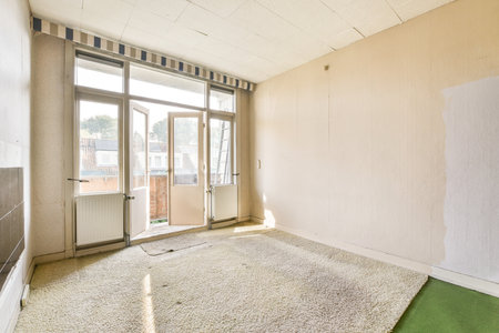 A spacious, vacant room featuring large windows that allow natural light, highlighting the potential for creative design and decoration.の写真素材