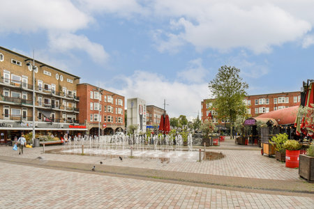 A lively town square featuring a beautiful fountain, vibrant shops, and lush greenery. Perfect for relaxation and social gatherings.の写真素材