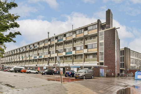 A contemporary residential building showcasing multiple stories, balconies, and an urban street view with vehicles parked along the curb.の写真素材