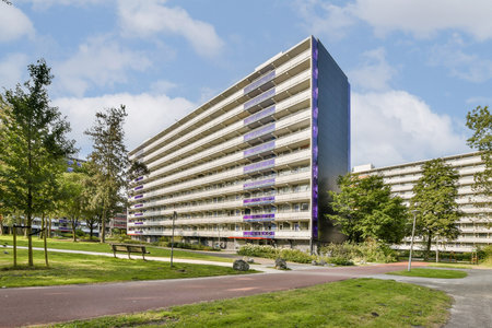 A striking modern residential building featuring multiple floors with large windows, set amidst beautifully landscaped greenery and pathways.の写真素材