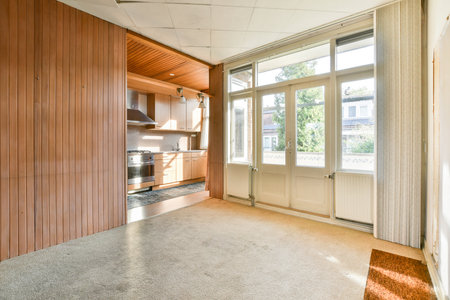 A spacious kitchen featuring sleek cabinets and large windows, allowing for abundant natural light. The flooring complements the warm wooden accents elegantly.の写真素材