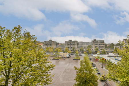 A view of a modern urban landscape featuring contemporary buildings, parking areas, and lush greenery, showcasing the blend of nature within a city environment.の写真素材