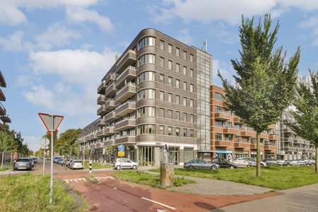 Contemporary architecture blends seamlessly with the streetscape, showcasing sleek design and greenery along a bustling city road.の写真素材