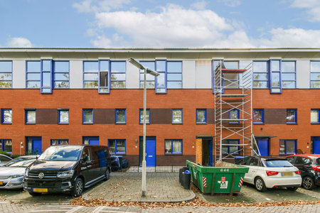 A contemporary building with multiple windows and a scaffold, set in an urban environment showcasing construction work and parked vehicles.の写真素材