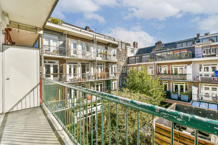 A vibrant view from a balcony showcasing multiple apartments with greenery and blue sky. The architecture reflects urban living with natural elements.の写真素材