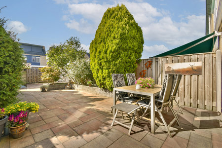 A bright patio featuring a neatly arranged outdoor seating area surrounded by greenery, perfect for relaxation or gatherings in a tranquil setting.の写真素材