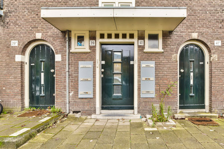 A quaint facade featuring three distinct doorways, each uniquely framed with green accents against a brick wall, reflecting a charming neighborhood vibe.の写真素材