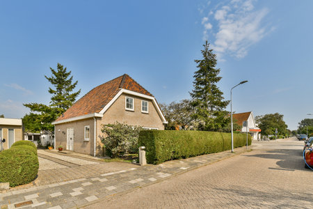 Vibrant residential area featuring a cozy house surrounded by well-maintained hedges and trees, showcasing a peaceful suburban vibe.の写真素材