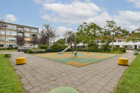 A peaceful urban park featuring grassy areas, trees, and a playground with slides. The layout invites relaxation and recreational activities for families.の写真素材