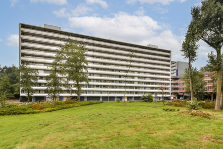 An impressive modern residential building stands amidst lush greenery, featuring large balconies and a spacious landscape perfect for community living.の写真素材