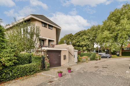 A contemporary home featuring a well-maintained garden and driveway, situated in a serene suburban neighborhood with lush greenery.の写真素材