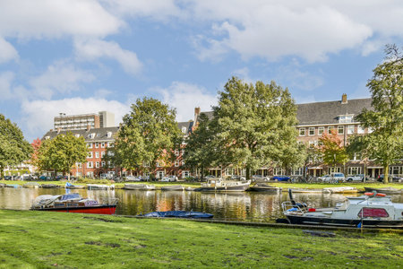 A picturesque view of a tranquil waterway, framed by vibrant buildings and lush trees, providing a charming atmosphere of urban nature.の写真素材