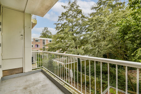 A modern balcony with a sleek railing offers a vantage point to admire the surrounding vibrant trees and landscaped area, perfect for relaxation and enjoyment of nature.の写真素材