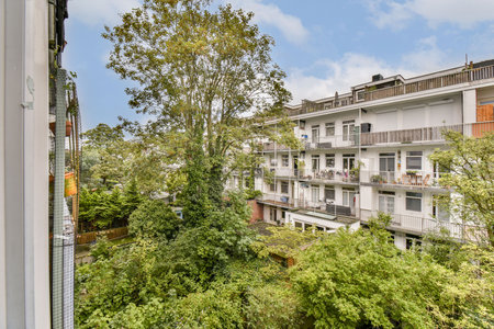 A scenic view from a balcony showcasing an urban apartment complex with lush greenery and trees nearby, creating a tranquil atmosphere in the city.の写真素材