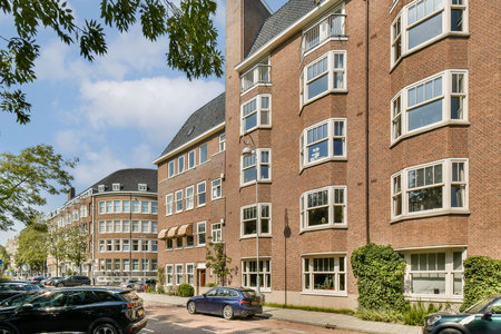 A view showcasing elegant modern buildings with large windows and unique design features, set in a vibrant urban environment filled with greenery.の写真素材