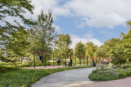 A vibrant outdoor fitness area with exercise equipment nestled within a lush, green park, showcasing people engaging in physical activities amidst trees.の写真素材