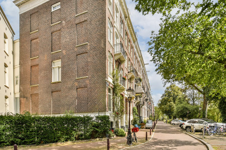 A street view showcasing a corner building with textured brickwork and lush greenery, adding charm to the urban environment.の写真素材