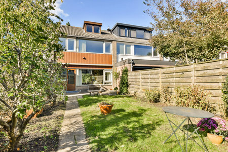 A beautifully landscaped garden featuring a modern house. The yard includes well-maintained plants and outdoor seating for relaxation.の写真素材