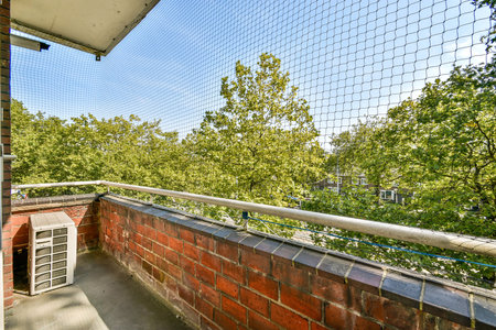 A charming balcony offers a scenic view filled with vibrant green trees under a clear blue sky, creating a serene atmosphere ideal for relaxation.の写真素材