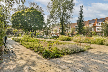 A tranquil park featuring a stone pathway lined with vibrant plants and trees, inviting visitors to enjoy natures beauty and relax.の写真素材