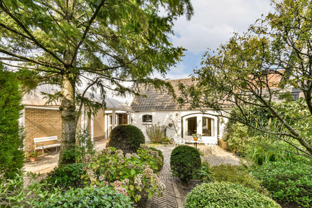 A picturesque garden featuring a variety of plants and trees, creating a tranquil and inviting atmosphere, perfect for relaxation and nature appreciation.の写真素材