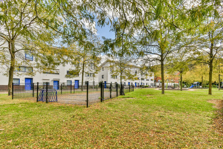 A serene residential playground surrounded by lush greenery and modern buildings, offering a peaceful environment for kids and families.の写真素材