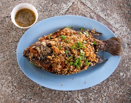 fried tilapia fish with crispy garlic on the table marble.の写真素材