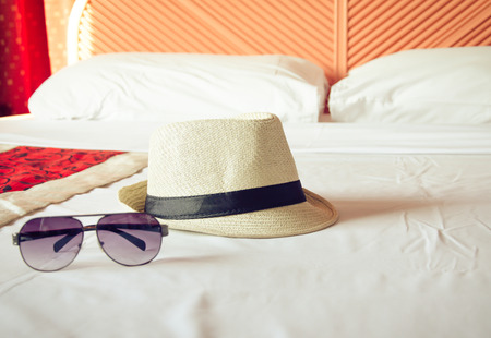 Straw hat and sunglasses on bed.の写真素材
