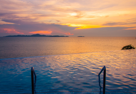 Luxury swimming pool in front of sea at during sunsetの写真素材