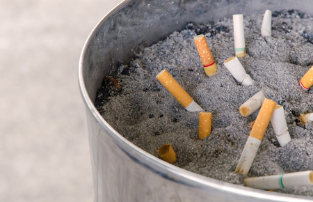 Smoked cigarettes in dirty ashtray with sand.の写真素材