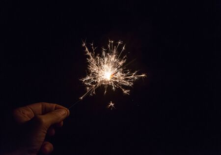 hand holding a sparkler fire on black background.の写真素材