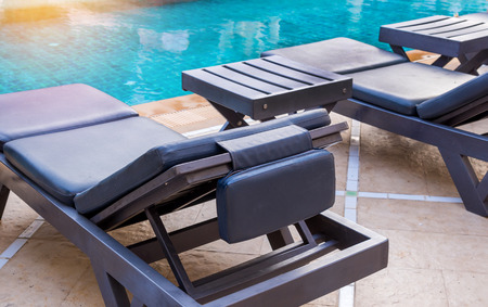 Luxury swimming pool with white deckchairs.