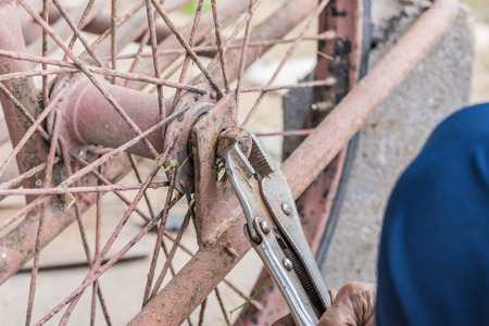 Close-up Of person hands repairs wheel bicycle with pliers.の写真素材