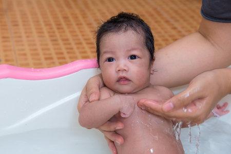 newborn baby taking a bath by mother at home, asian child.の写真素材