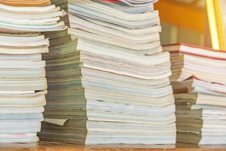 Many books pile on wooden table at library.