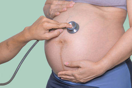 doctor exams Pregnant woman with stethoscope in hospital.の写真素材
